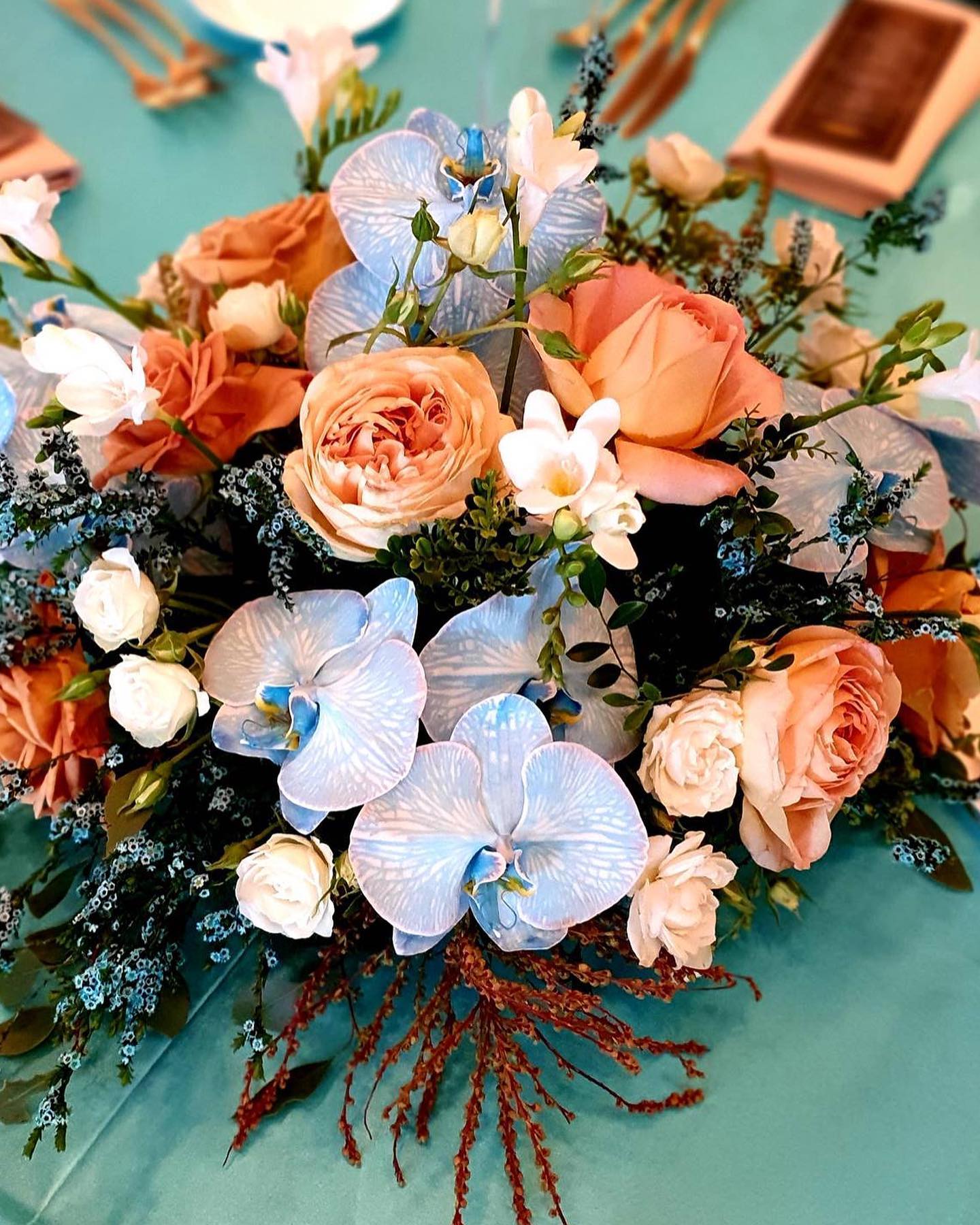 - Oh I Do Like to Be Beside the Seaside…
Beach inspired centrepieces with aquamarine orchids and driftwood vibes peeking through the roses. Tinted Thryptomene for a splash of sea spray and buddy Andromeda to mimic the sand dune Tussock grass.